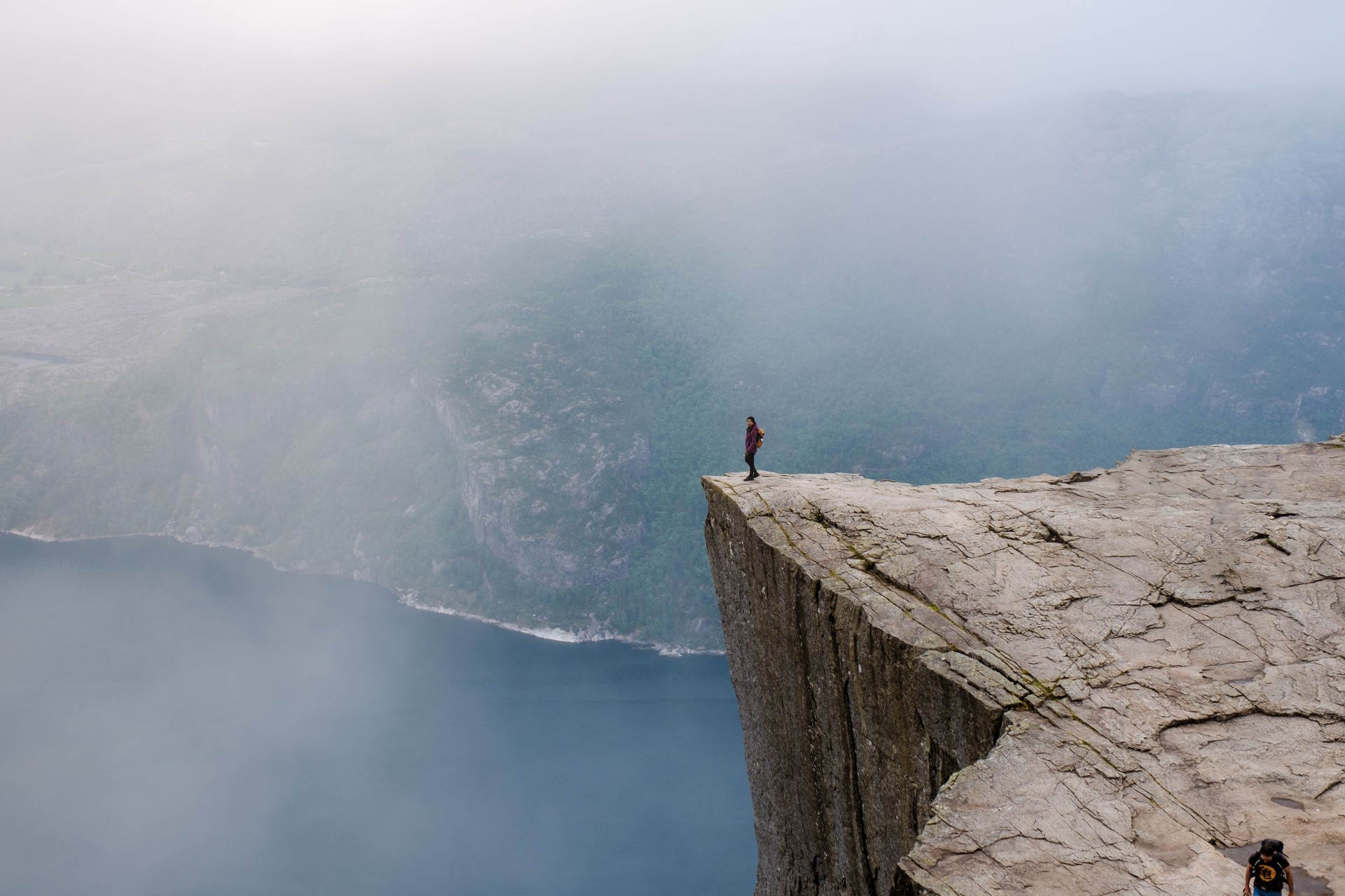 A lone hiker stands on the precipice of a dramatic cliff in Norway,Preikestolen, Norway