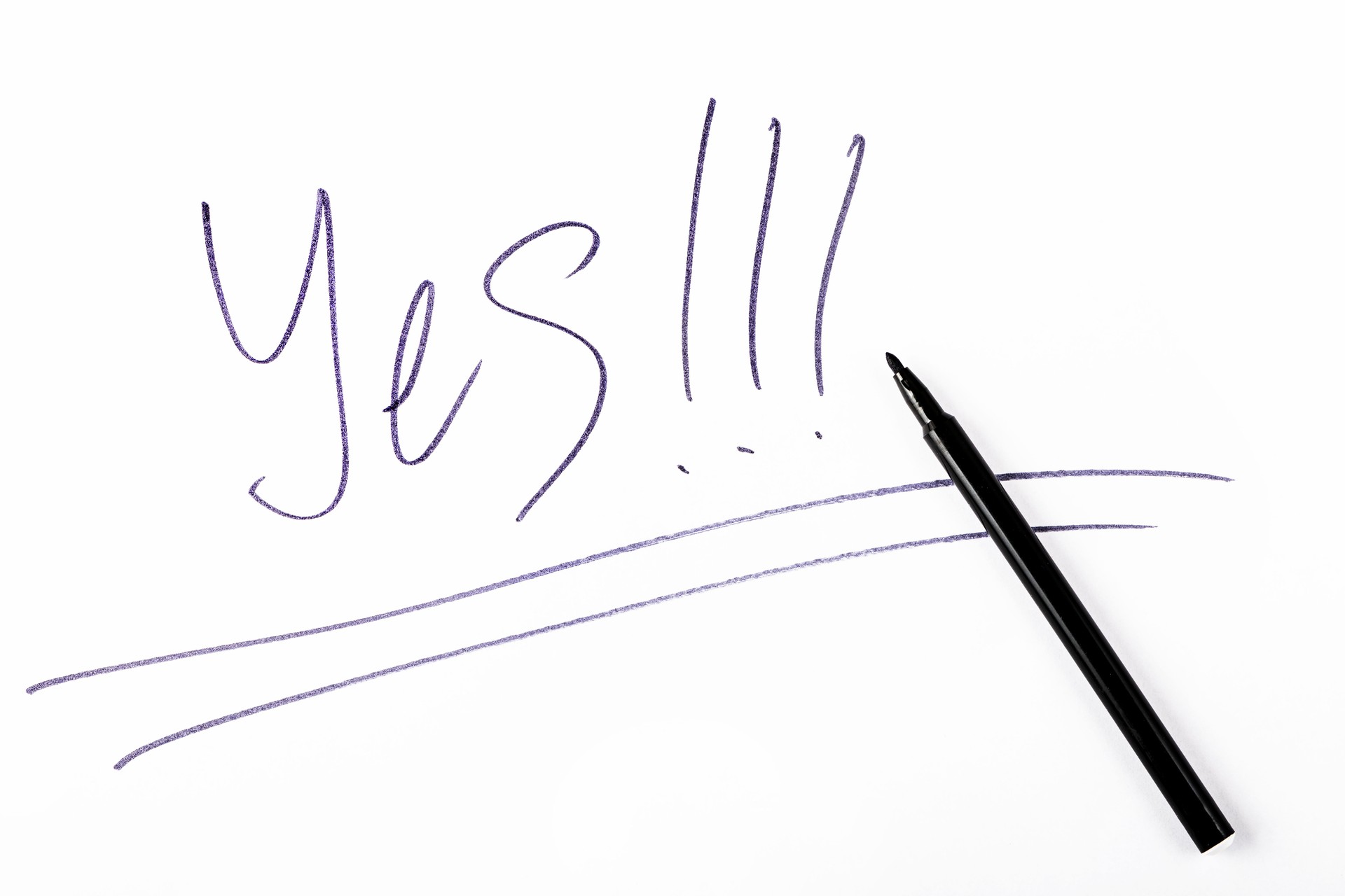 The word "Yes!!!" written with a black felt-tip pen on a white sheet of paper